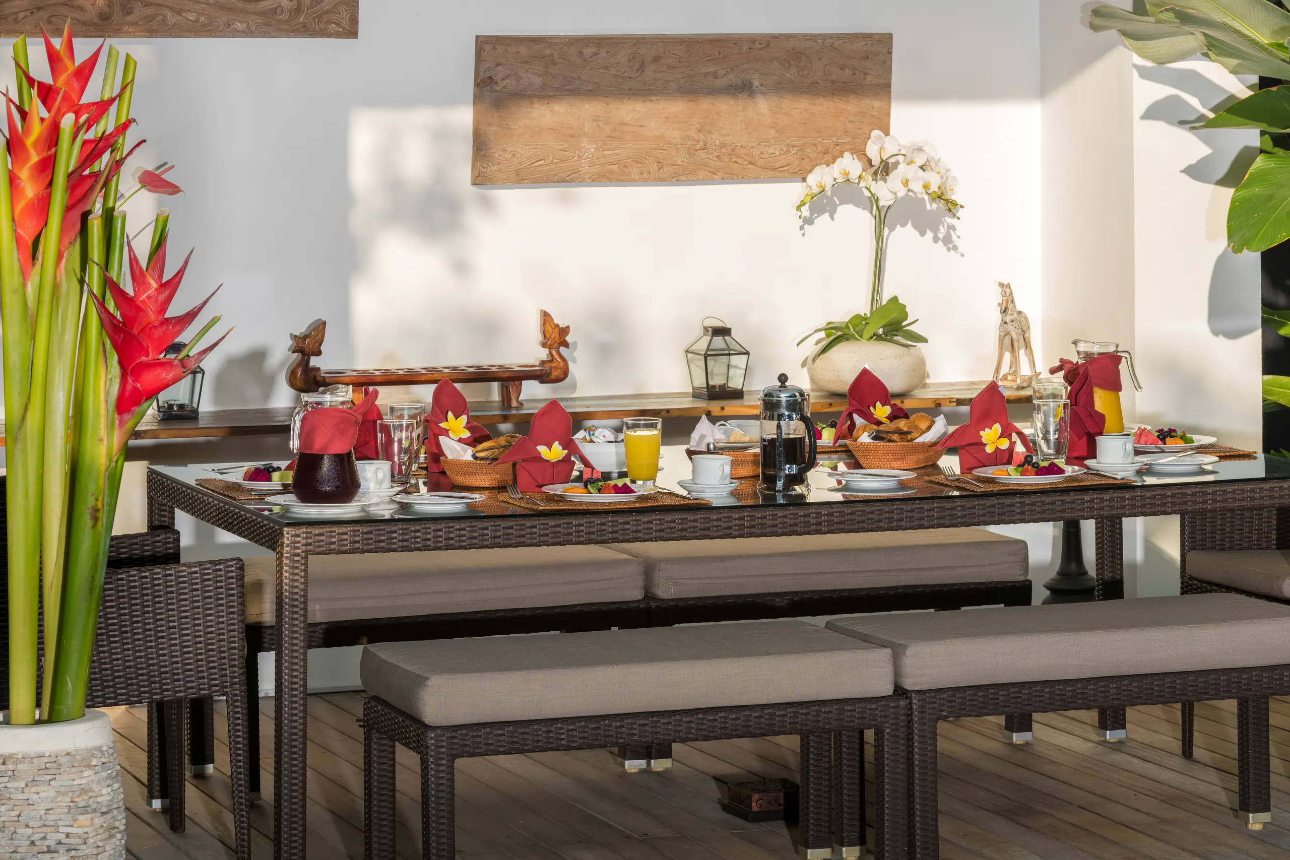 The table in the poolside balé at Casa Brio, laid with red napkins and cut fruit beneath tall heliconia