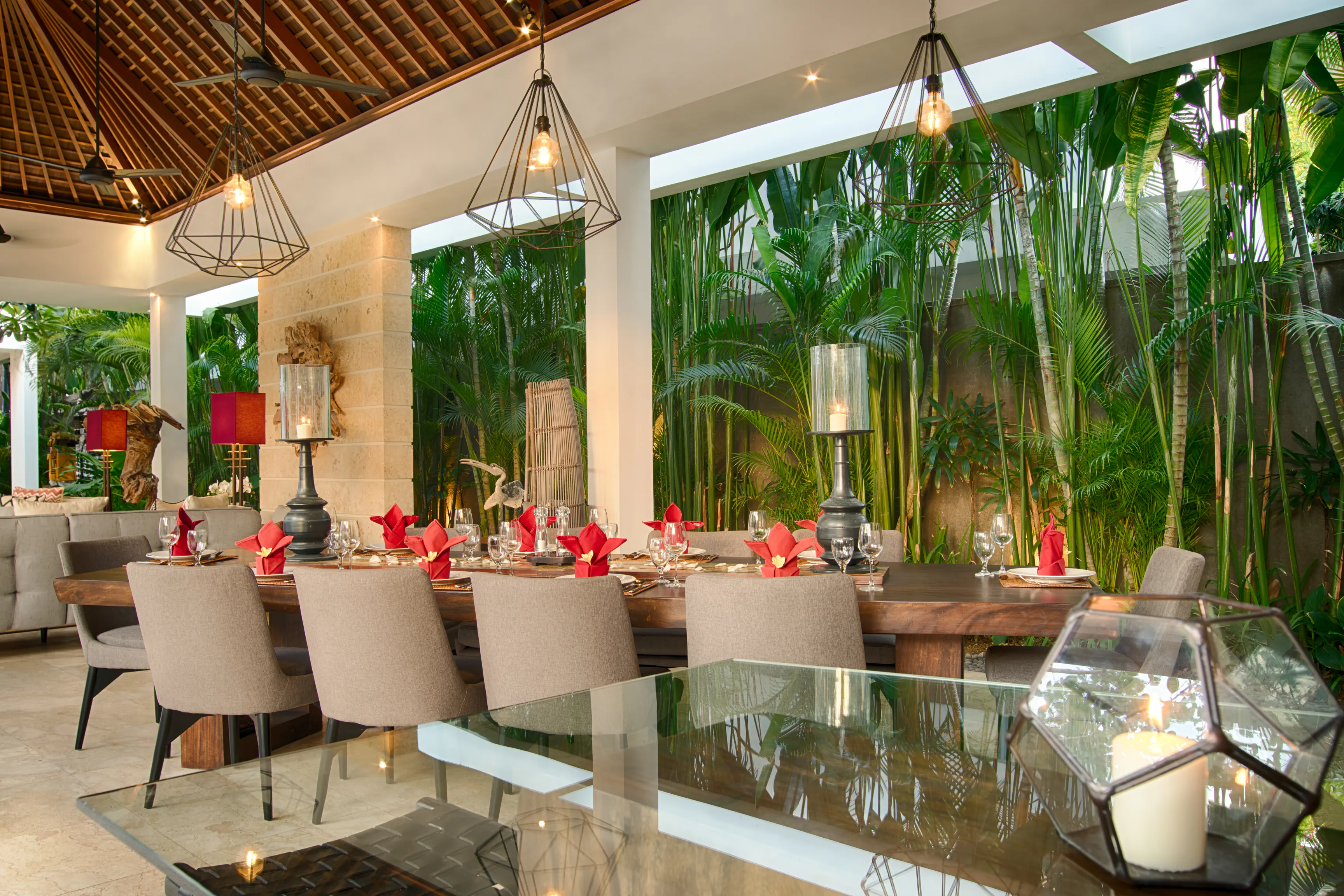 The Suarwood dining table in the pavilion at Casa Brio, laid with red napkins under copper pendant lights