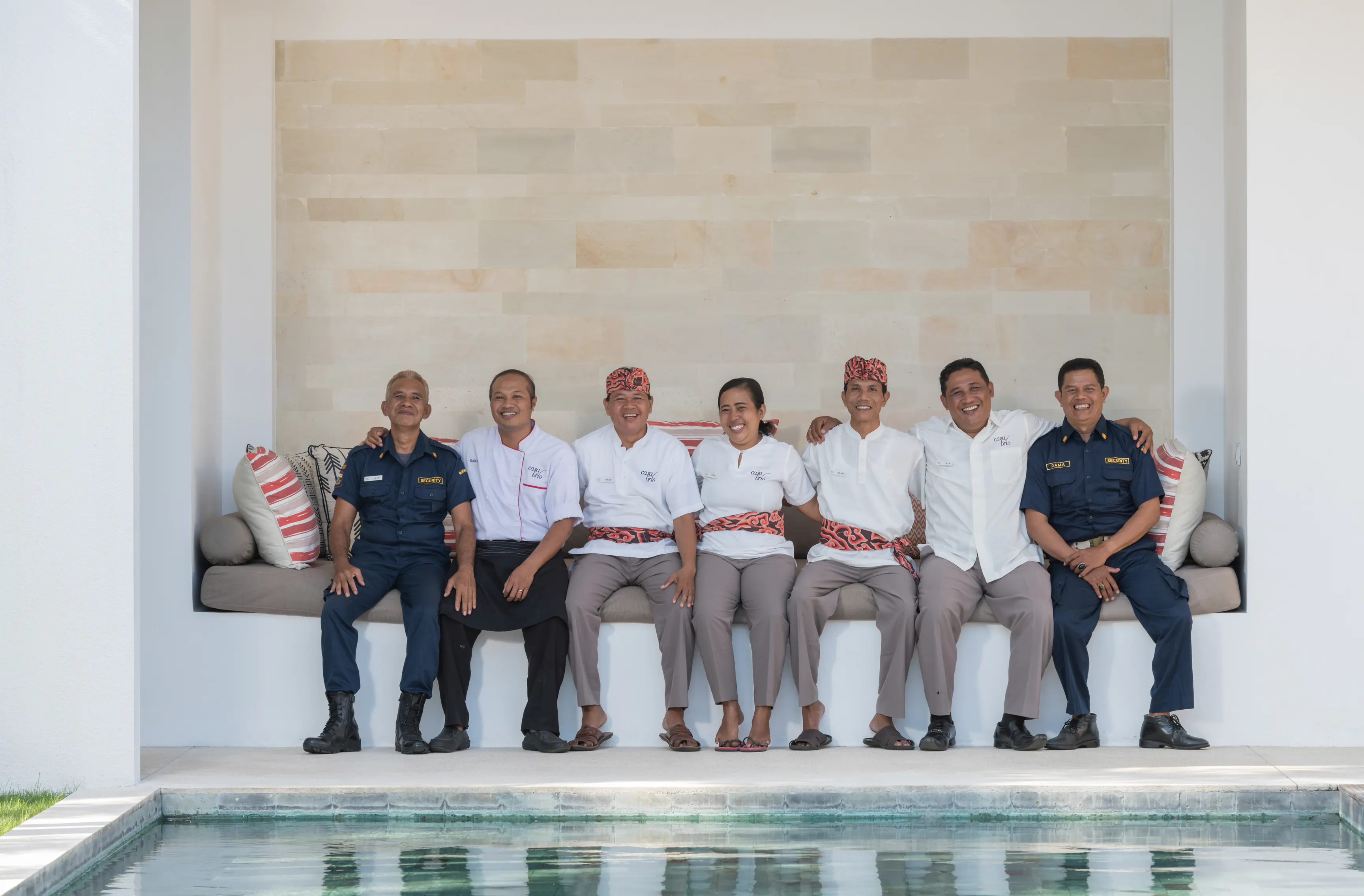 Seven of the Casa Brio house team seated together on a bench at the villa