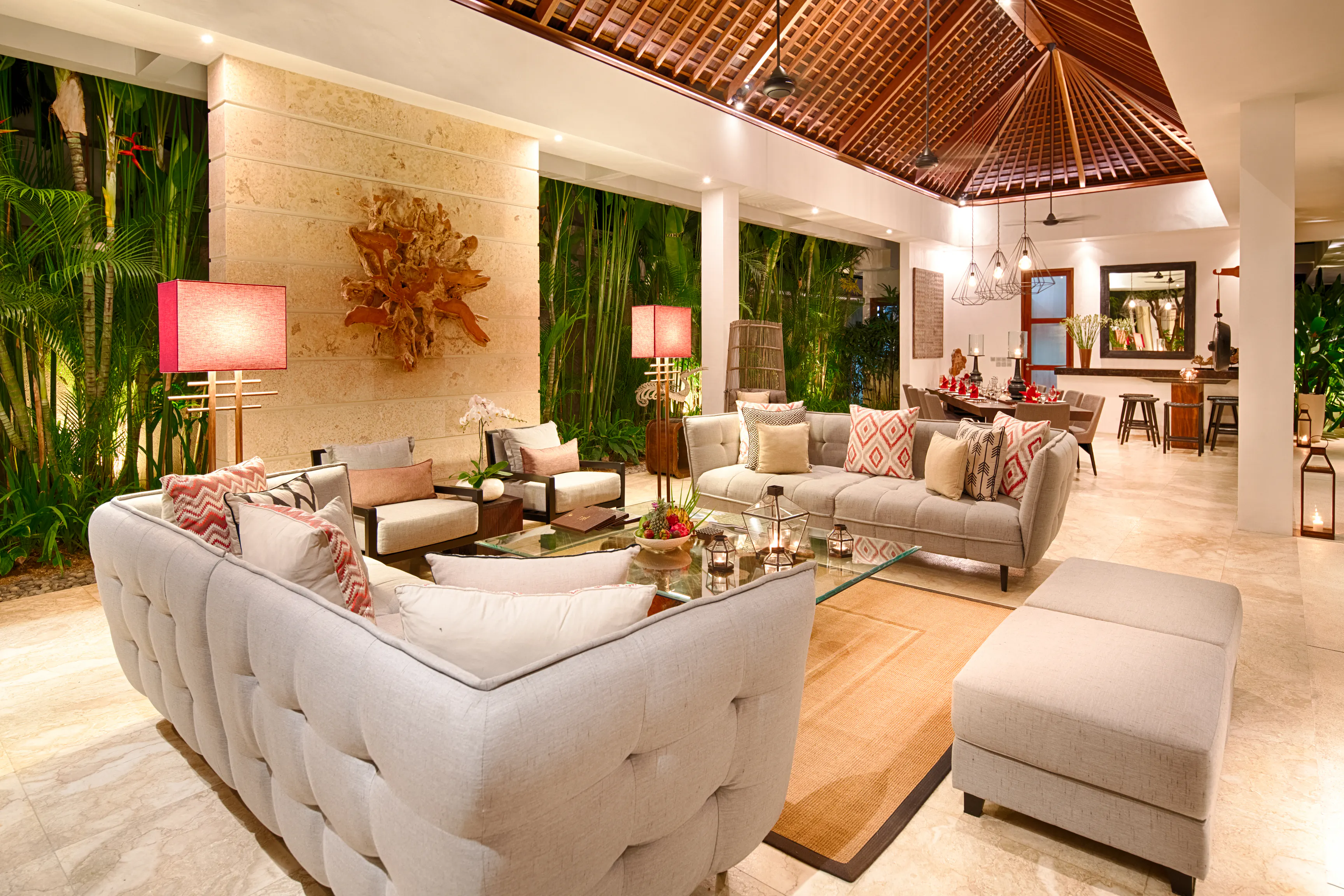 The open-sided living pavilion at Casa Brio, deep sofas under a vaulted alang-alang roof with the dining table beyond