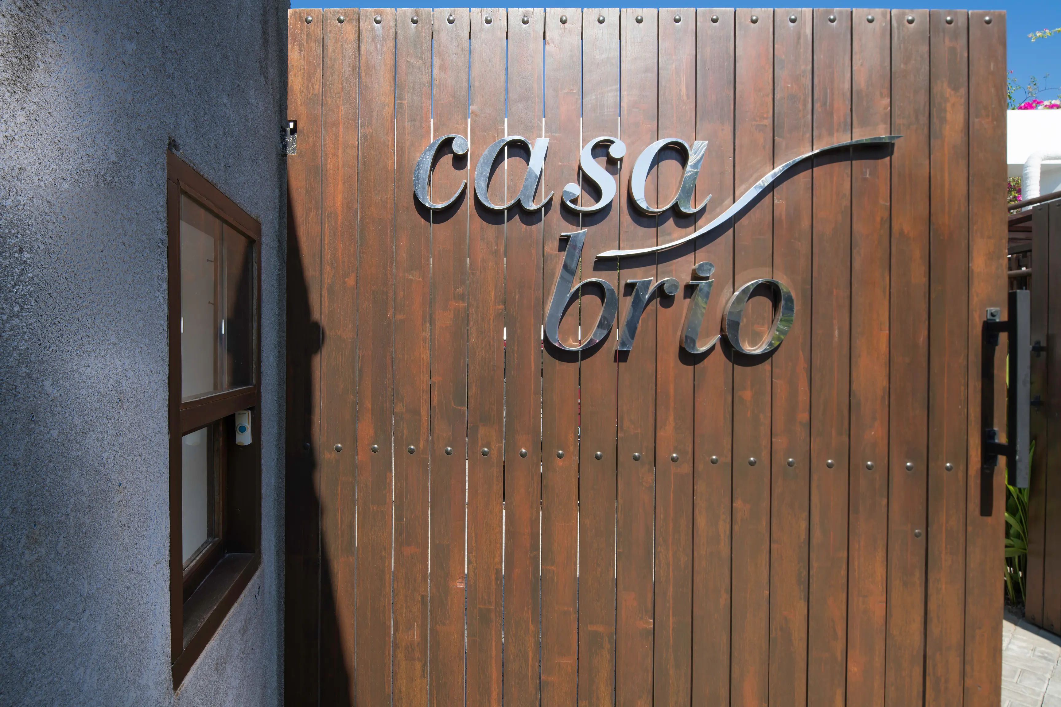 The timber street gate at Casa Brio, the villa name cut in steel across the boards, on the lane in Petitenget